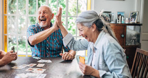 older couple playing cards and giving each other a high five